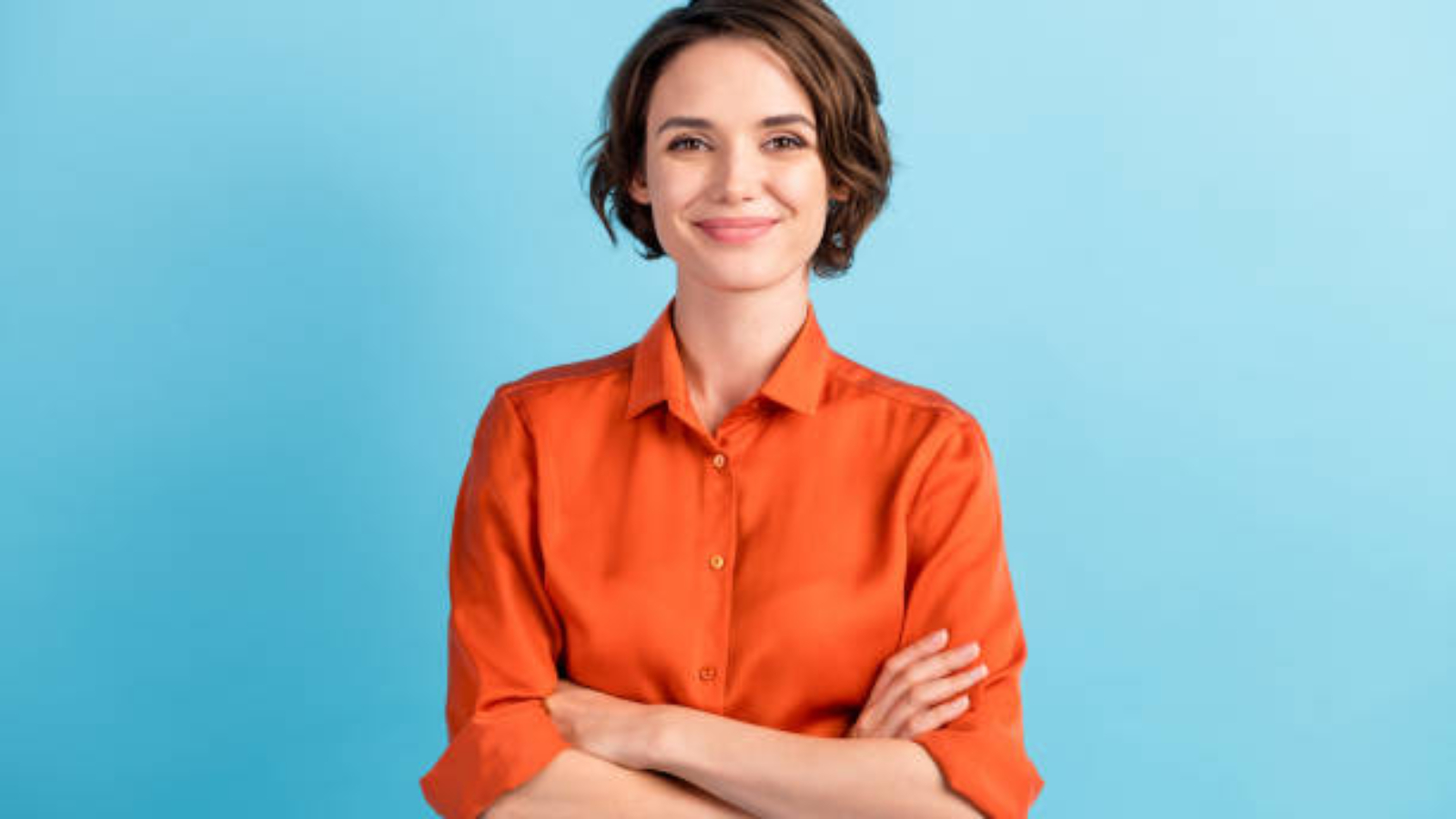 Photo of attractive charming lady cute bobbed hairdo arms crossed, self-confident person worker friendly smile good mood wear orange office shirt isolated blue color background