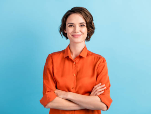 Photo of attractive charming lady cute bobbed hairdo arms crossed, self-confident person worker friendly smile good mood wear orange office shirt isolated blue color background